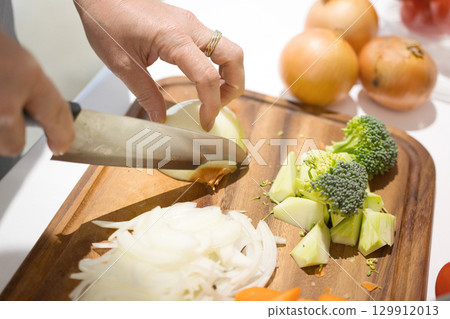 Hands of a middle-aged woman cutting vegetables 129912013
