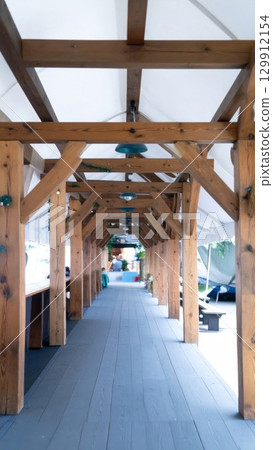 Long Wooden Beam Walkway Tunnel with Supporting Pillars and Overhead Canvases 129912154