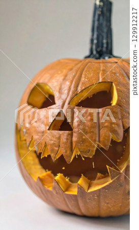Carved Orange Halloween Pumpkin with Glowing Expression and Dark Stem in Studio Setting 129912217