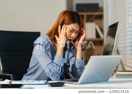 Stress businesswoman is sitting at table, under stress from working 129913418