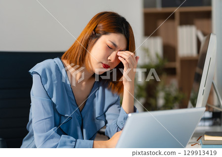 Stress businesswoman is sitting at table, under stress from working Stress businesswoman is sitting at table, under stress from working 129913419