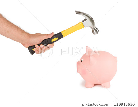 Man holding a hammer and breaking a piggy bank 129913630
