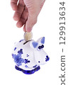 Piggy bank in a shape of a cow with blue ornament, coin falling 129913634