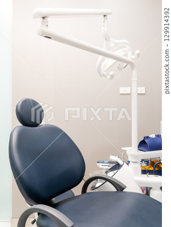Vertical view of modern blue dentist chair with lamp 129914392