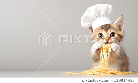 Adorable kitten chef playing with pasta in cute white hat 129914485
