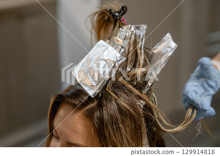 Hair coloring process with foils applied at a salon on a sunny afternoon Hair coloring process with foils applied at a salon on a sunny afternoon 129914818