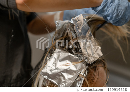 Hair coloring process with foil highlights in a salon during daytime 129914838