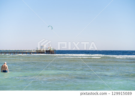 Kite surfing activity at a beach pier in Egypt on a sunny day with clear skies 129915089