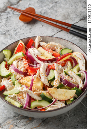Dak Nangchae Korean chicken salad with cucumber and apple tossed with tangy sesame mustard dressing closeup on the plate. Vertical Dak Nangchae Korean chicken salad with cucumber and apple tossed with tangy sesame mustard dressing closeup on the plate. Vertical 129915530
