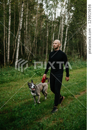 Man Walking Dog in Forest Path with Calm Expression Man Walking Dog in Forest Path with Calm Expression 129915656