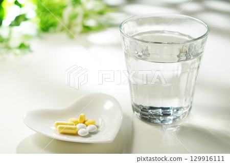 Tablets and capsules of medicine and a glass of mineral water 129916111