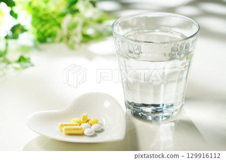 Tablets and capsules of medicine and a glass of mineral water Tablets and capsules of medicine and a glass of mineral water 129916112