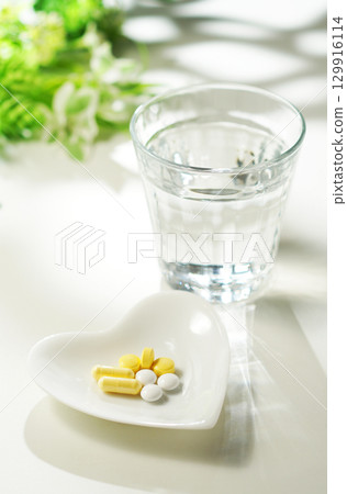 Tablets and capsules of medicine and a glass of mineral water 129916114