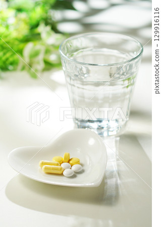 Tablets and capsules of medicine and a glass of mineral water Tablets and capsules of medicine and a glass of mineral water 129916116