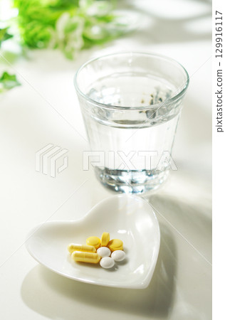 Tablets and capsules of medicine and a glass of mineral water 129916117