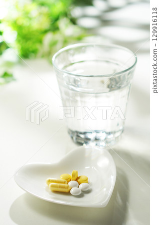 Tablets and capsules of medicine and a glass of mineral water 129916118
