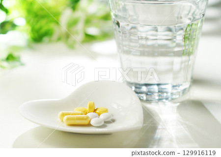 Tablets and capsules of medicine and a glass of mineral water Tablets and capsules of medicine and a glass of mineral water 129916119