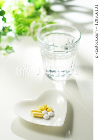 Tablets and capsules of medicine and a glass of mineral water 129916131