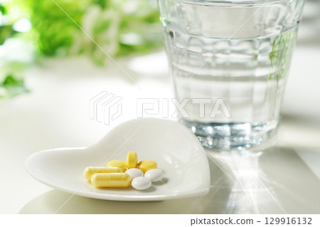 藥片和膠囊以及一杯礦泉水 129916132