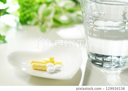 Tablets and capsules of medicine and a glass of mineral water 129916136
