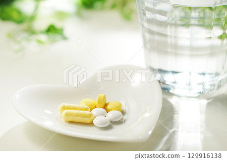 Tablets and capsules of medicine and a glass of mineral water Tablets and capsules of medicine and a glass of mineral water 129916138