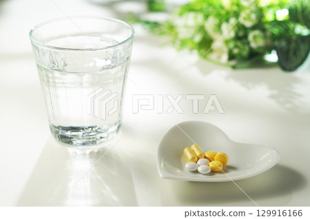 Tablets and capsules of medicine and a glass of mineral water 129916166