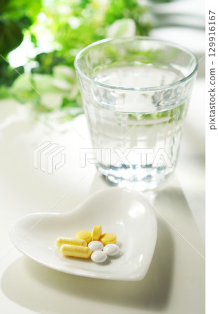 Tablets and capsules of medicine and a glass of mineral water Tablets and capsules of medicine and a glass of mineral water 129916167