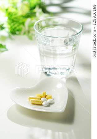 Tablets and capsules of medicine and a glass of mineral water Tablets and capsules of medicine and a glass of mineral water 129916169