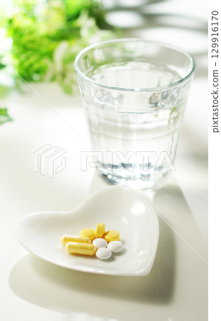 Tablets and capsules of medicine and a glass of mineral water Tablets and capsules of medicine and a glass of mineral water 129916170