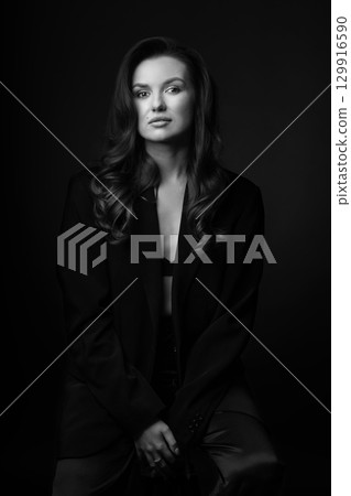 Beautiful woman with dark suit and wavy hair studio portrait 129916590