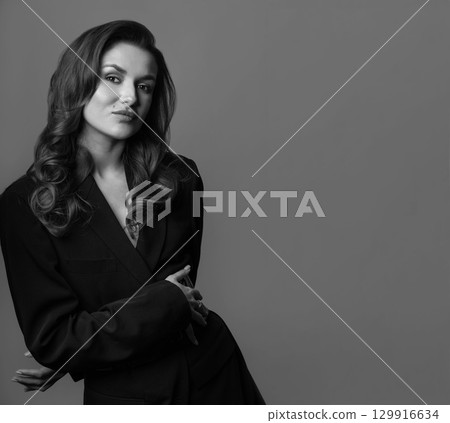 Woman with long wavy hair and black suit studio portrait 129916634