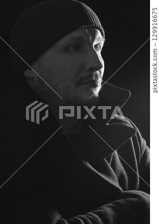 Serious man with black winter coat and winter hat studio portrait Serious man with black winter coat and winter hat studio portrait 129916675
