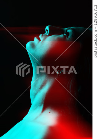 Beautiful woman face silhouette portrait illuminated with light in RGB color split effect style and dark background 129916712