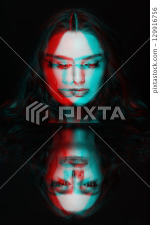 Portrait of beautiful woman with wavy hair and face reflection in mirror in RGB color split effect style 129916756