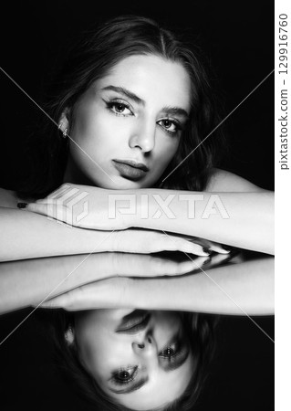 Portrait of beautiful woman with wavy hair and make-up face reflection in mirror 129916760