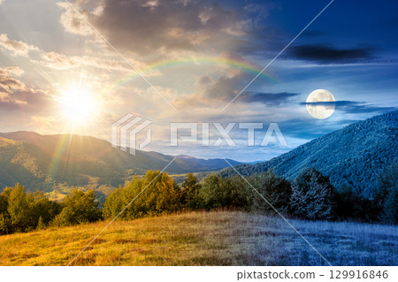 mountain landscape with forest on the hill on autumn equinox. day and night time change concept. beautiful view in to the rural valley. alpine countryside scenery with sun and moon at twilight mountain landscape with forest on the hill on autumn equinox. day and night time change concept. beautiful view in to the rural valley. alpine countryside scenery with sun and moon at twilight 129916846