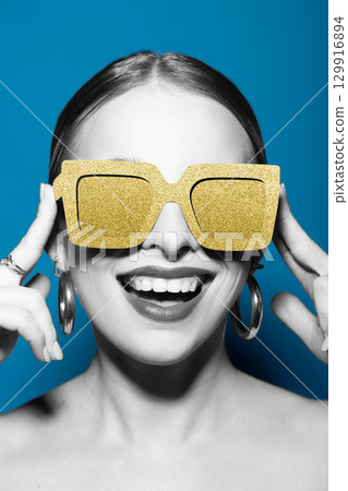 Woman portrait with classic hairstyle and golden retro sunglasses in blue background 129916894
