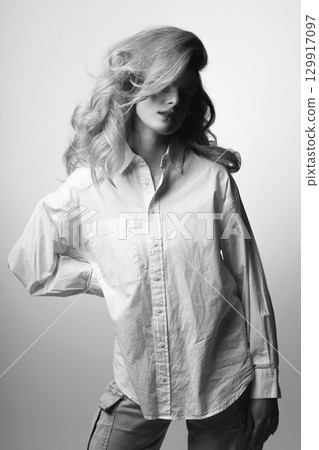 Beautiful woman with big wavy hair and white shirt studio portrait 129917097