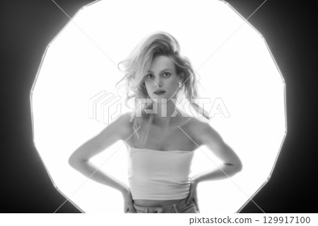 Beautiful woman with big wavy hair black and white studio portrait in bright illuminated soft box background 129917100