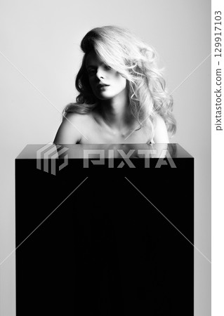 Beautiful woman with big wavy hair and black cube black and white studio portrait 129917103