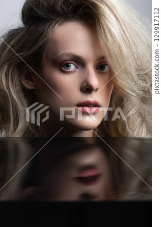 Beautiful woman with big wavy hair and black mirror reflection studio portrait Beautiful woman with big wavy hair and black mirror reflection studio portrait 129917112