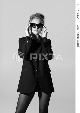 Beautiful woman with black suit and sunglasses black and white studio portrait portrait 129917287