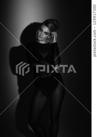 Beautiful woman with tight black clothes black and white studio background 129917300