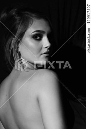 Beautiful woman with naked back and palm leaf black and white studio portrait 129917307