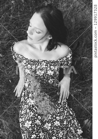 Woman in Floral Dress Resting on Grass 129917328