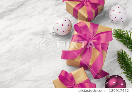 Gift box present with pink bow ribbon and christmas ball and tree ornament on marble table background, top view 129917432