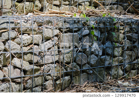 Stones piled up on wire mesh 129917470