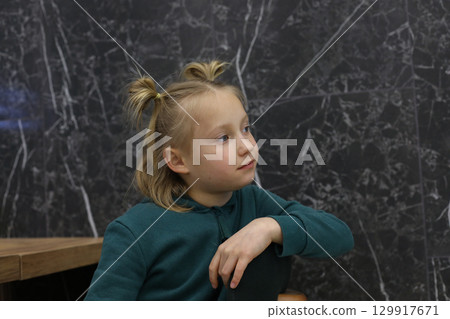 Smiling blond child girl sitting in lounge. Young girl 6 years old portrait 129917671