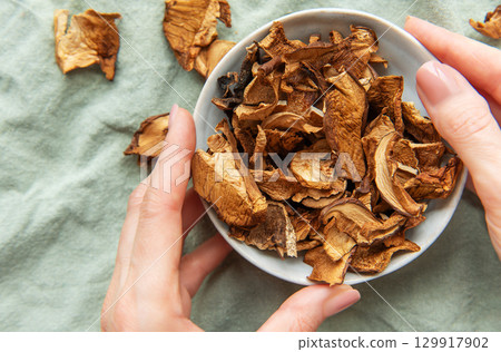 Chef holding bowl of dried mushrooms on green tablecloth Chef holding bowl of dried mushrooms on green tablecloth 129917902