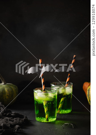 Halloween green cocktails garnish fun black bat on black background. Festive drink, spooky setting, featuring eerie elements and playful holiday decor. 129918074